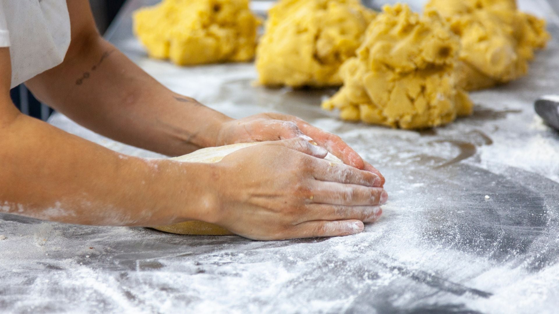 Person kneading dough at Candied Bakery